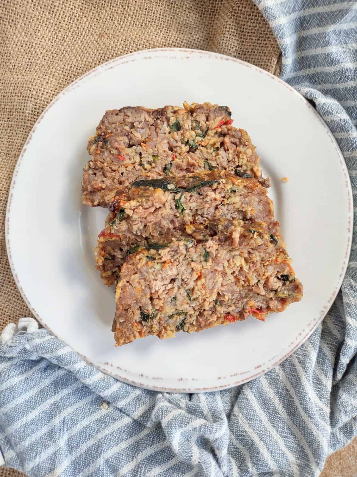 Meatloaf filled with veggies on a white plate with brown trim.