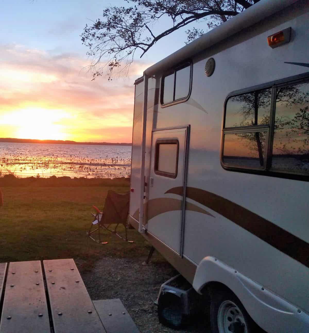 A travel trailer next to the Mississipp River at sunset.