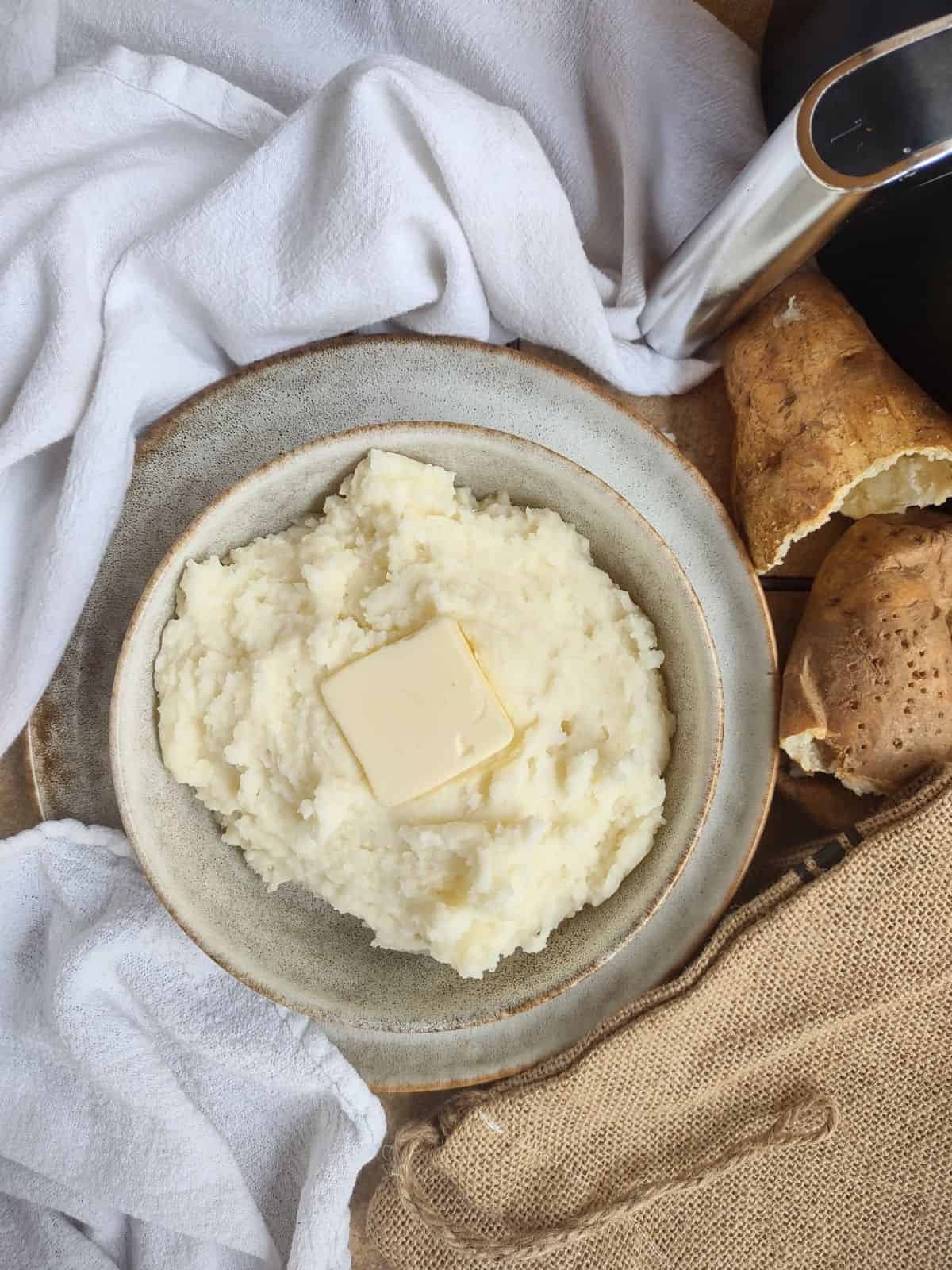 A bowl of air fryer mashed potatoes with a pat of butter on top.