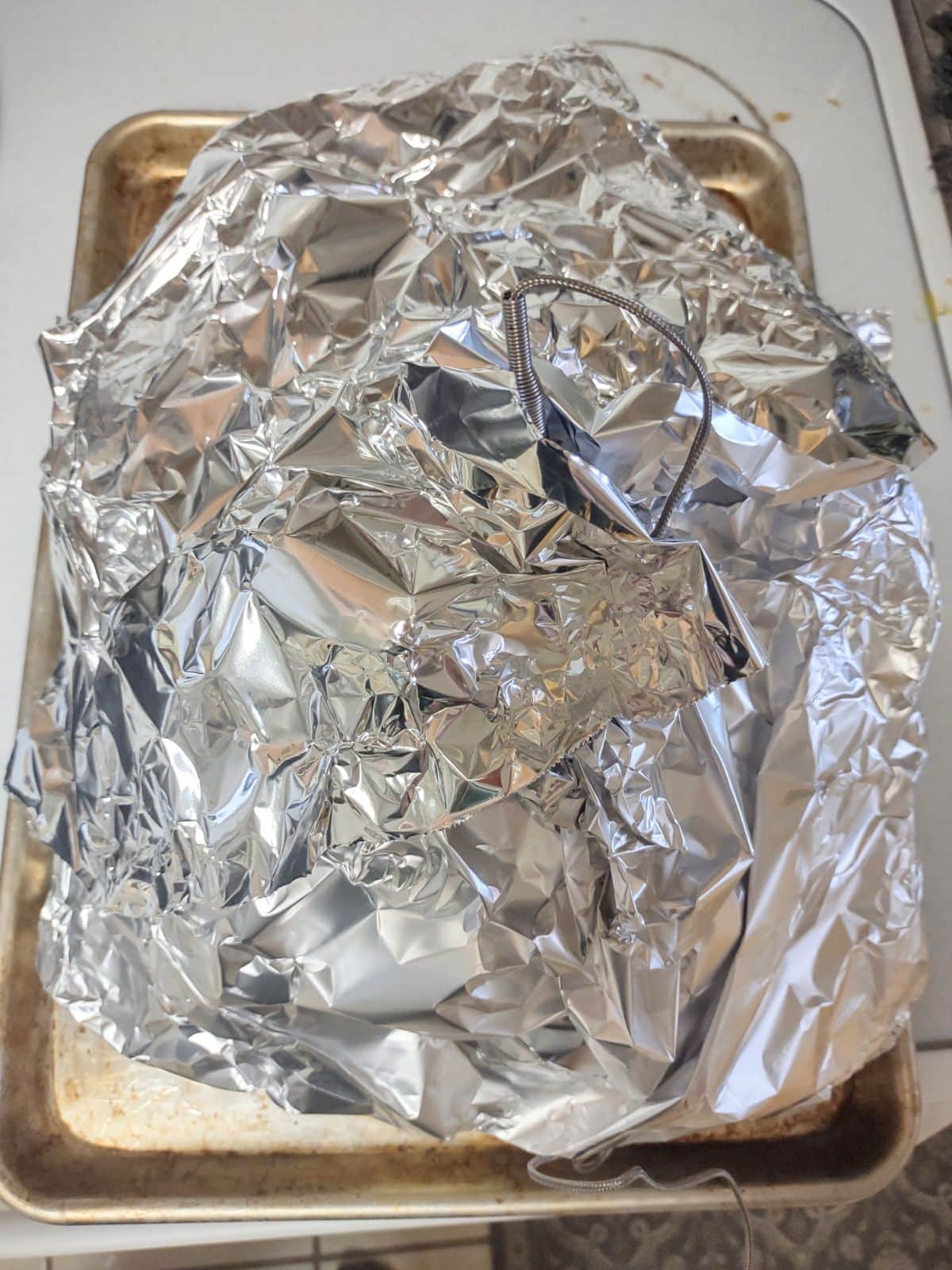 Foil covering a smoked turkey on a sheet pan.