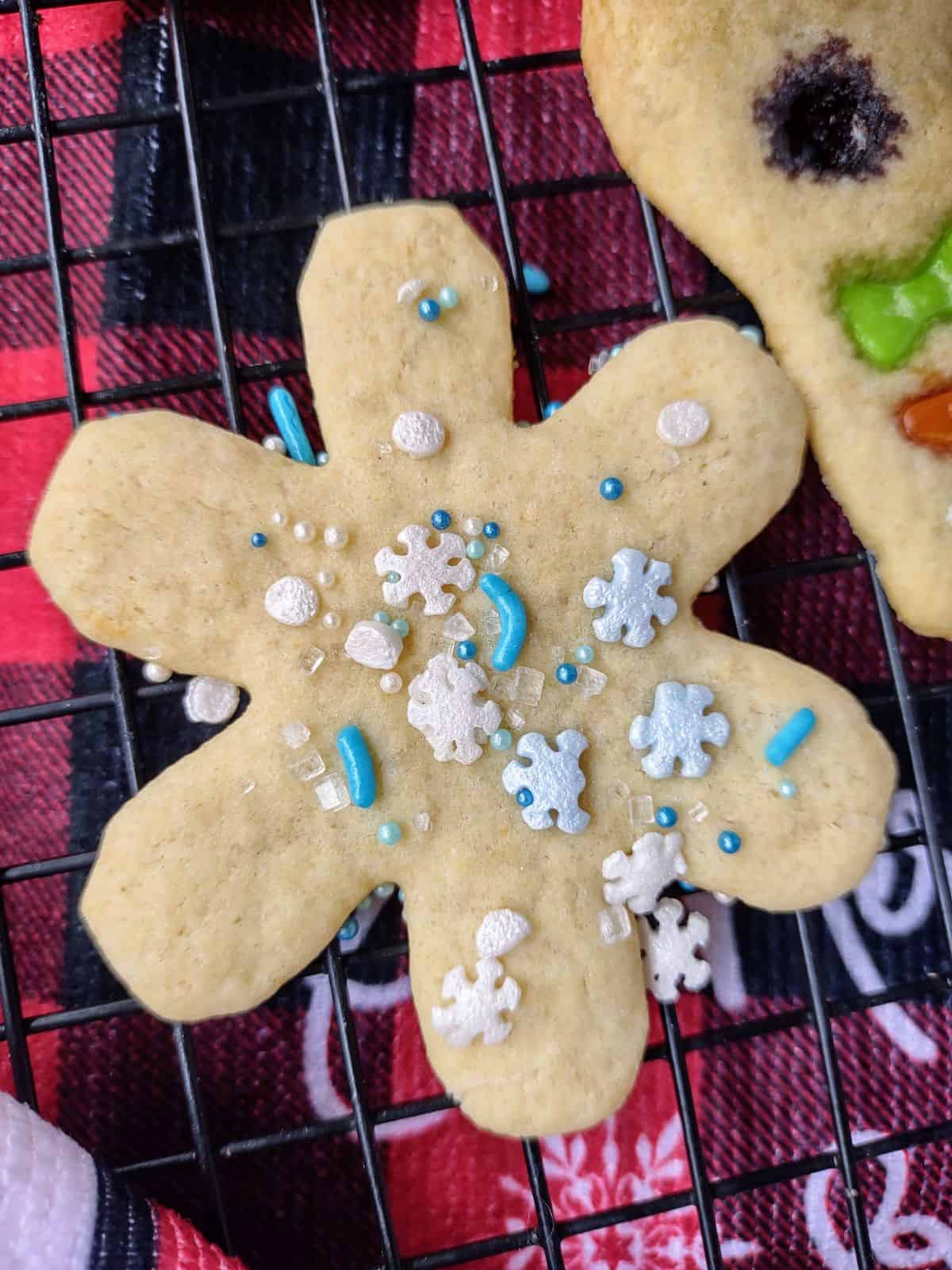 A snowflake cookie decorated with sprinkles on a drying rack.