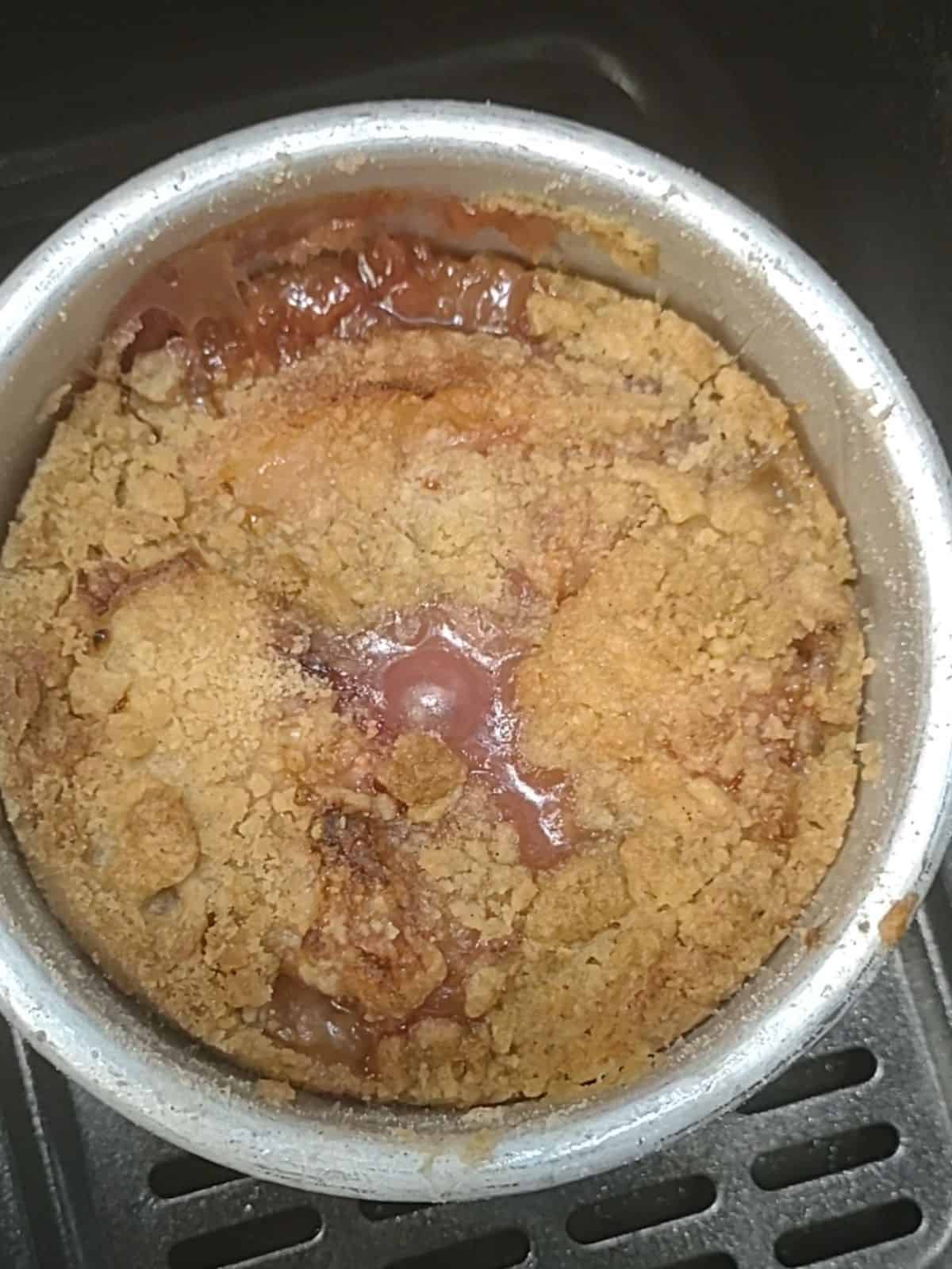 A close up of the white peach cobbler inside the basket of an air fryer.