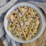 A white bowl filled with a pasta salad containing mayo, smoked turkey, onion, and diced celery.