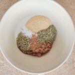 A mix of salt and spices for a brine in a white bowl