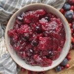 A bowl filled with cranberry sauce that contains fresh blueberries and cardamom