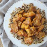 Piece of dark meat chicken coated in a Clementine glaze on top of a bed of tri-colored quinoa