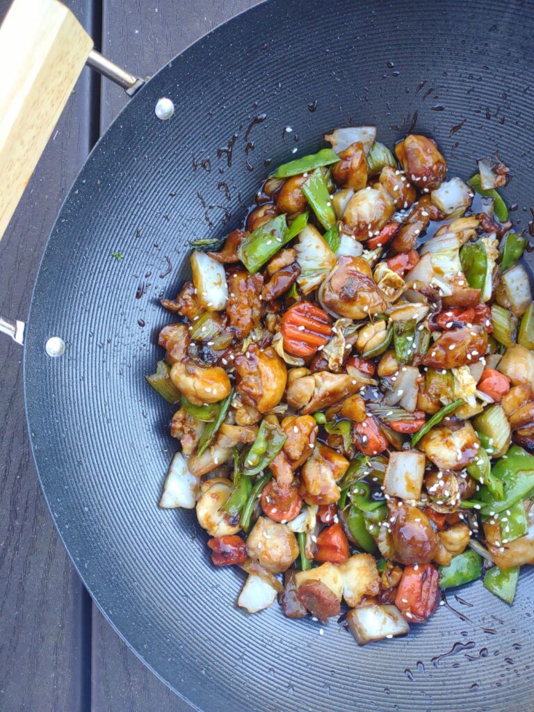 Teriyaki Chicken with loads of vegetables coated in sauce inside of a wok