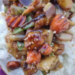Teriyaki Chicken with loads of vegetables coated in sauce on white rice that is zoomed in