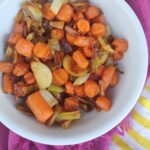Buttered crinkle cut carrots with leeks in a white bowl.
