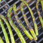 Charred Asparagus sitting on a grill grate.