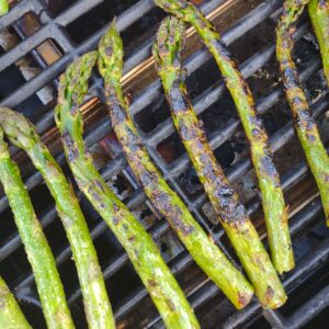 Charred Asparagus sitting on a grill grate.