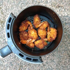 Kirkland Panko Fried Shrimp cooked inside a round air fryer basket on the ground.