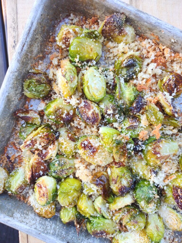 Roasted Brussels sprouts on a sheet pan with Panko breadcrumbs and Parmesan cheese.