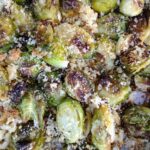 Up close view of roasted Brussels sprouts on a sheet pan with Panko breadcrumbs and Parmesan cheese.