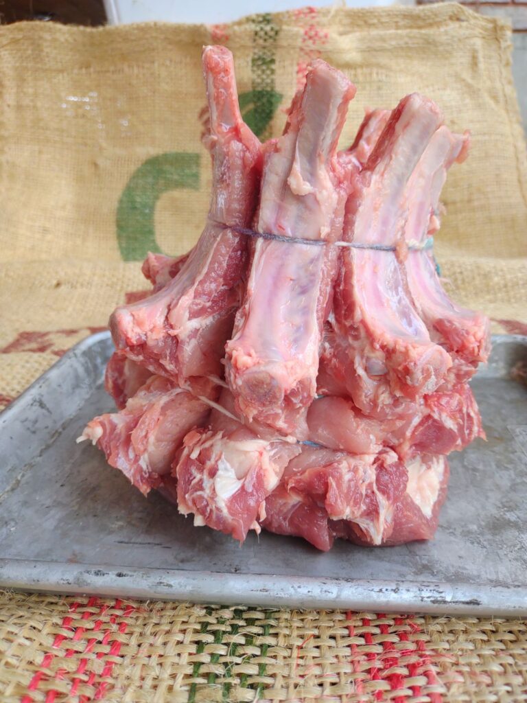 A raw crown rack of pork on a sheet pan.