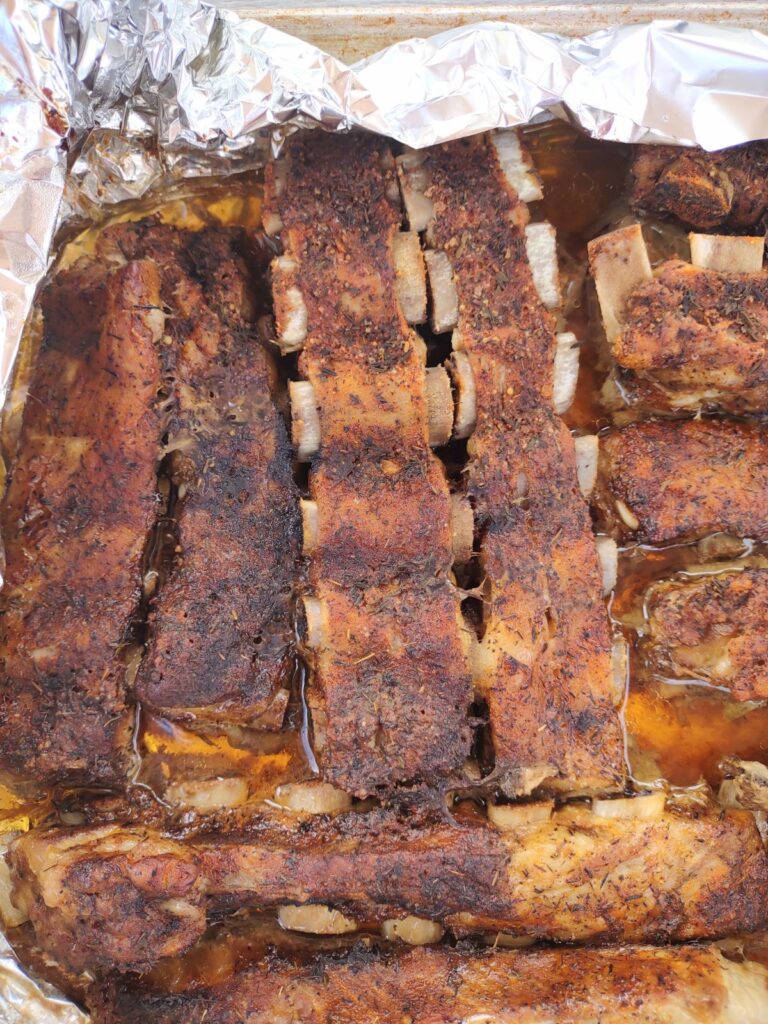 Dry rubbed St. Louis pork ribs on foil on a sheet pan.