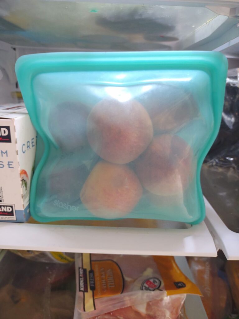 Peaches inside of a blue stand up stasher bag.