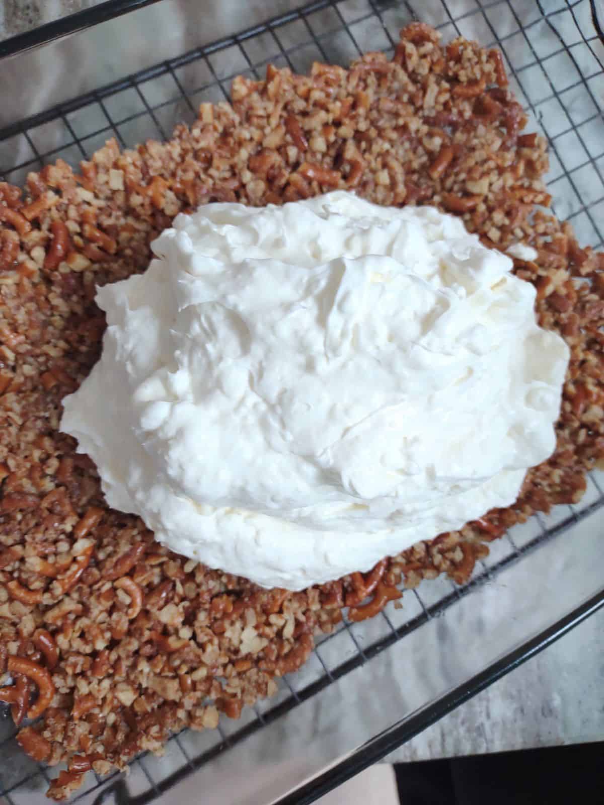 Cream layer being spread onto a pretzel crust.