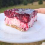 A slice of Mixed Berry Jell-O pretzel salad on a white plate outdoors.