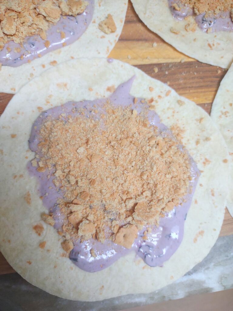 Tortillas with blueberry cream cheese dip spread on them with crushed graham crackers on top.