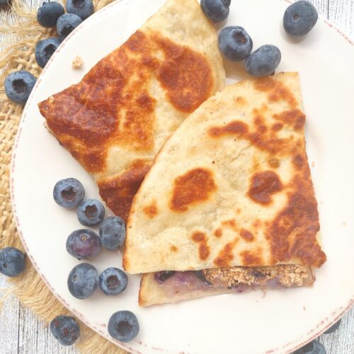 Blueberry Cheesecake Quesadillas on a plate with fresh blueberries.