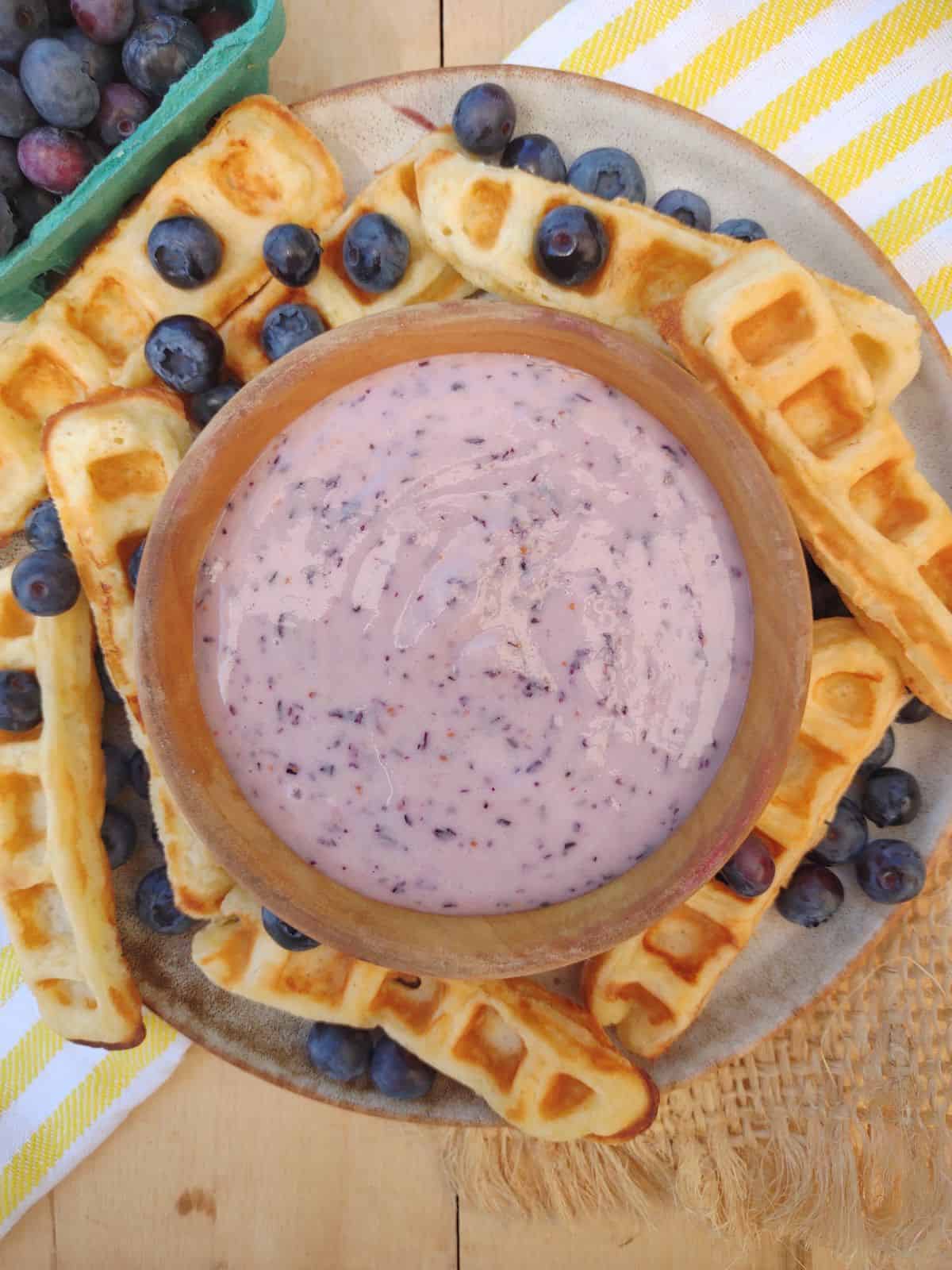 Blueberry cream cheese dipping sauce with waffle sticks on a plate.