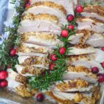 Juicy turkey breast cooked in the Instant Pot arranged on a sheet pan with fresh rosemary and cranberries.