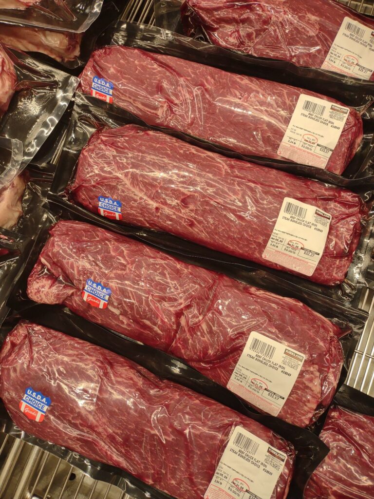 Packages of flat iron steak that are vacuum sealed at Costco on display.