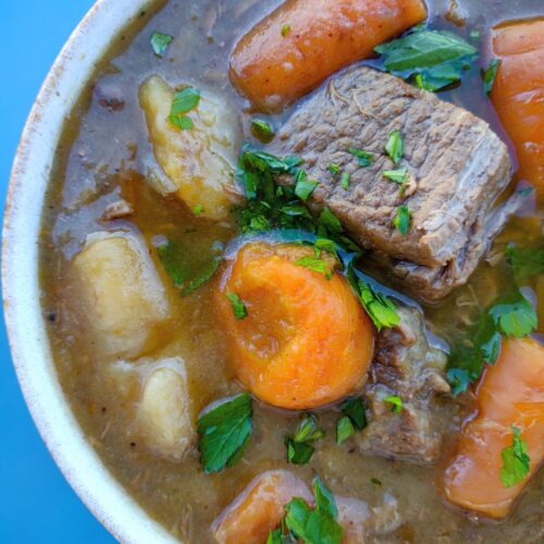 Close up of a bowl of beef stew that was thicken by potato flakes and contains beef stew meat, carrots, potatoes, and parsley.