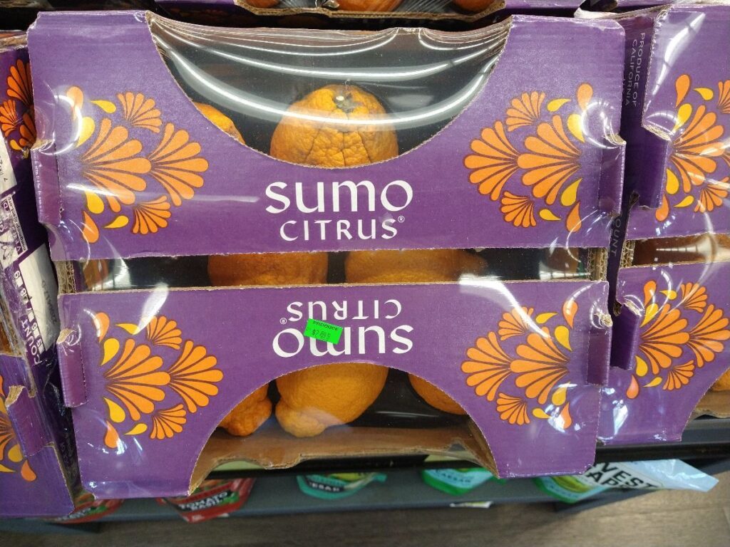A purple and orange case of Sumo Citrus mandarins at a grocery store.