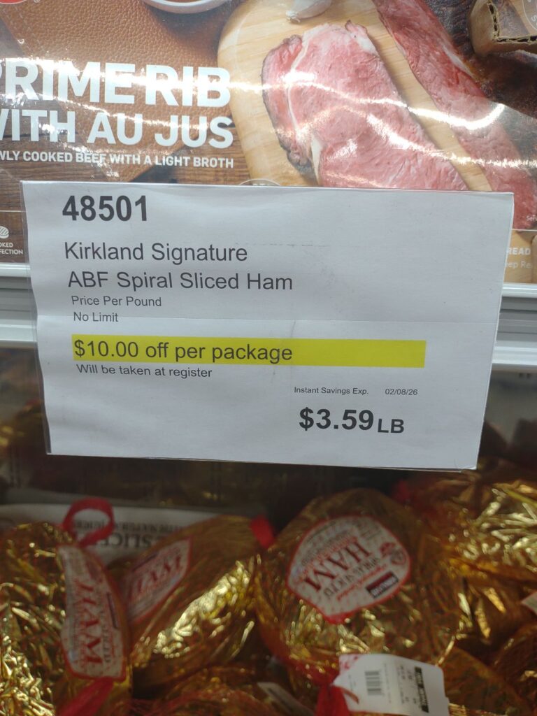 A sign showing a $10 off discount on Kirkland brand spiral sliced hams at Costco