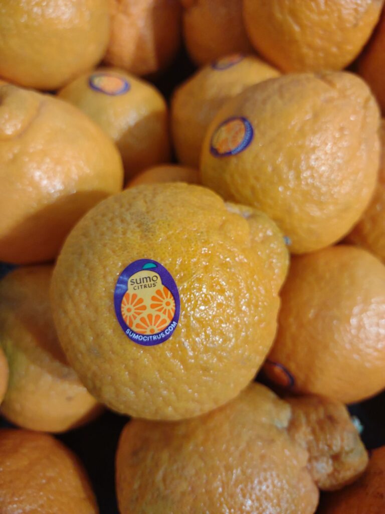 A display of Sumo oranges on display at a Smith's grocery store in Utah. The fruit has a purple and orange PLU sticker on the front.