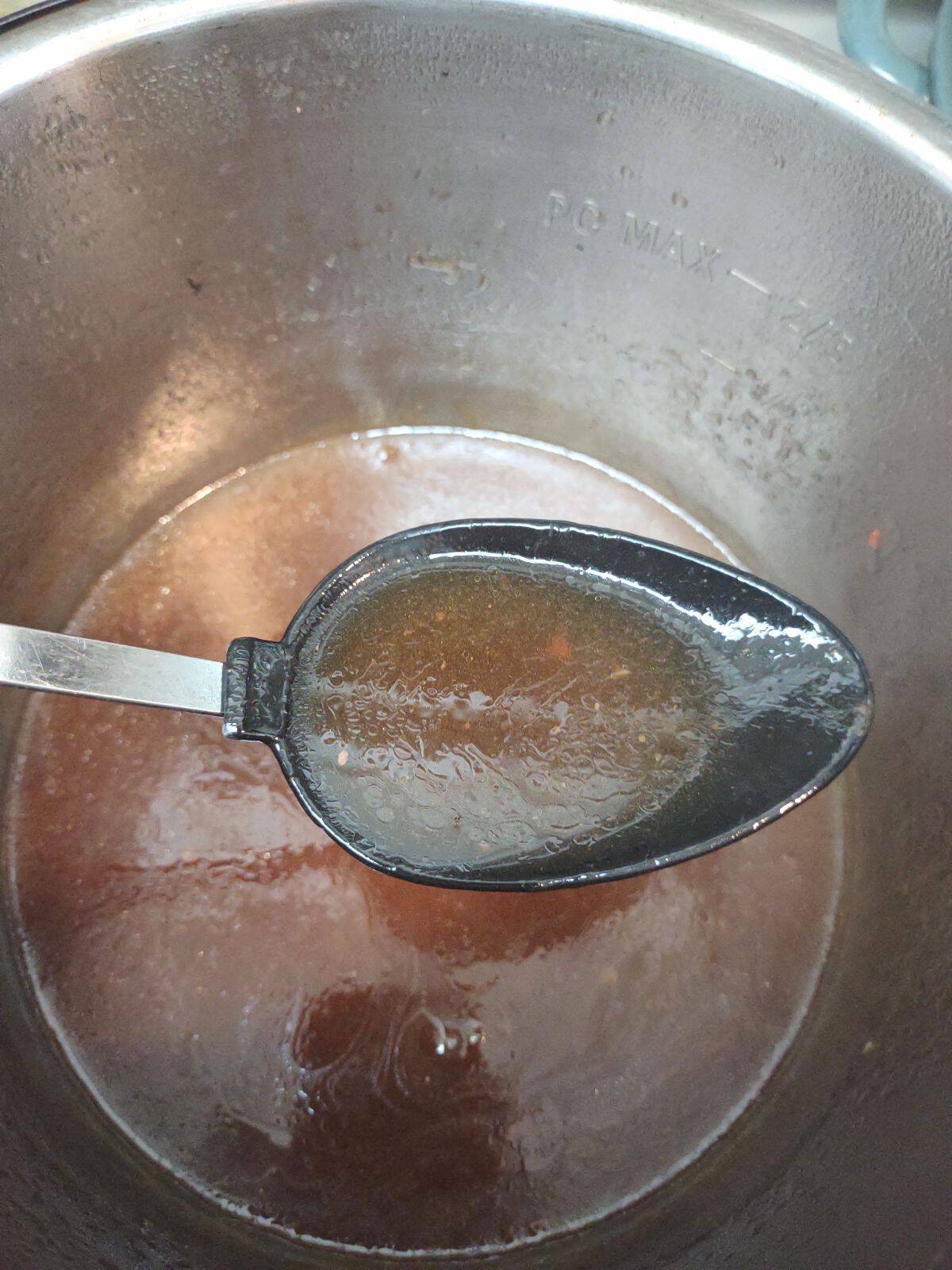 A spoon showing the cooking liquid in the Instant Pot