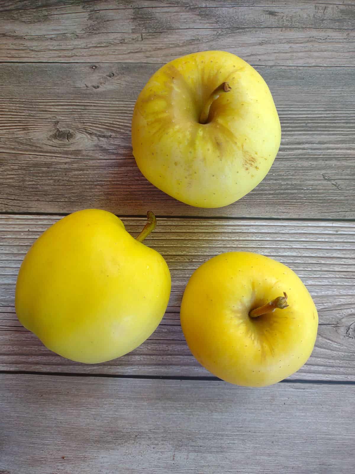 3 Blondee apples, showing the the browning around the stem, and one apple on its side. All the apples are on a picnic table.