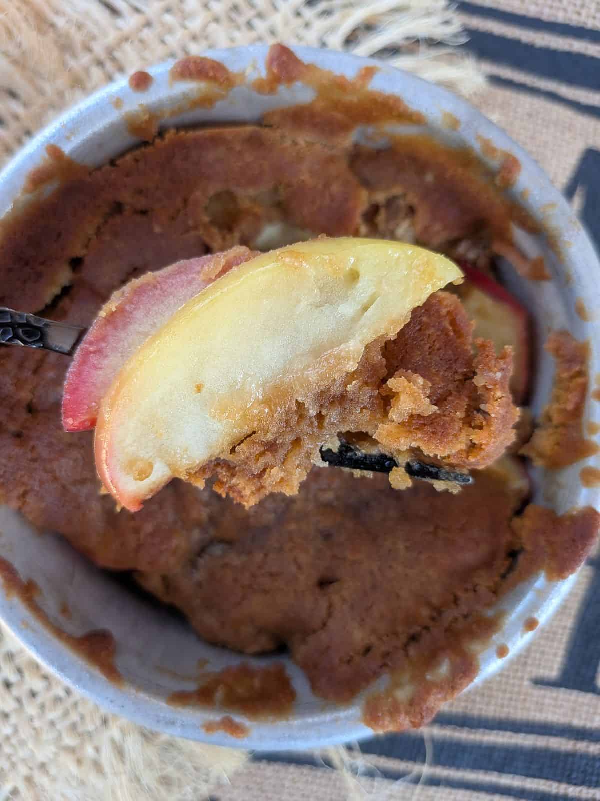 An apple cobbler made with Crimson Crisp apple, with a slice of the apple shown on a fork that it holds its shape when cooked.